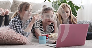 Girls watching media content on laptop while eating popcorn at home