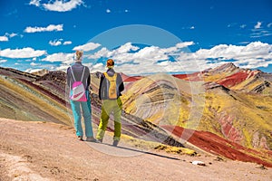 Girls watching stunning view at Palccoyo rainbow mountain Vinicunca alternative, mineral colorful stripes in Andean valley, photo