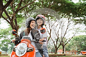 girls wearing helmets and jackets chatting while riding motorbikes together