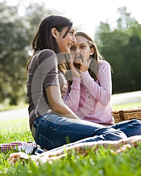 Girls whispering to each other at picnic in park