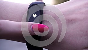 The girls wore a fitness bracelet. Girl checks pulse on fitness bracelet or activity tracker pedometer on wrist, sport