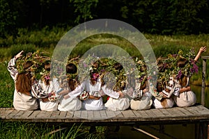 Girls in woven wreaths of different flowers and grass on a warm summer day.