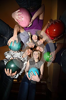 Girls and youths stand in close circle with balls