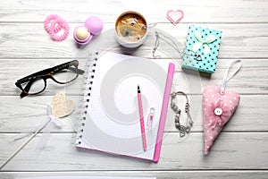 Girly accessories with notebook, cup of coffee and gift box on w