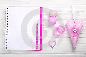 Girly pink accessories with blank notebook on white wooden background