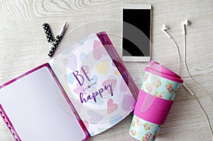 Girly thermos, notebook, phone and headphones on white wooden table photo