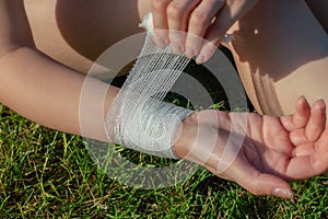 The girlâ€™s hands independently apply an antibacterial medical bandage to her wrist after falling down. First aid after hand