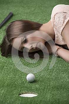 Girlâ€™s lying on grass with golf ball