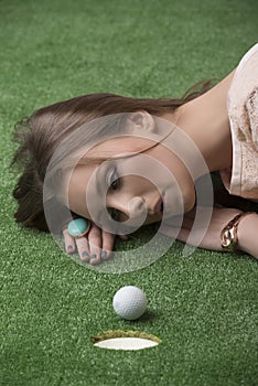 Girlâ€™s lying on grass with golf ball