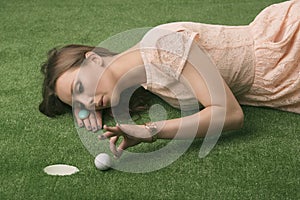 Girlâ€™s lying on grass with golf ball