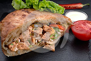 Giros, pita with chicken, sauce and vegetables, on a dark background photo