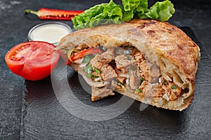 Giros, pita with chicken, sauce and vegetables, on a dark background photo