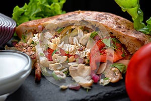 Giros, pita with pork meat, mushrooms, sauce and vegetables, on a dark background photo