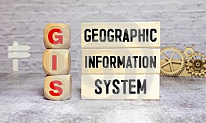 GIS - Geographic Information System write on a book isolated on Wooden Table.