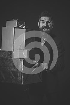 Gits to everyone. Man or businessman holds pile of gifts on black background.