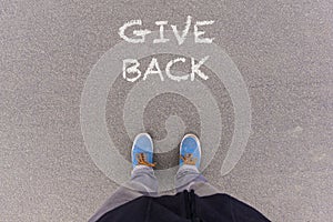 Give Back text on asphalt ground, feet and shoes on floor