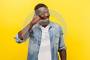 Give me a call! Portrait of playful happy handsome man making call me gesture. indoor studio shot isolated on yellow background