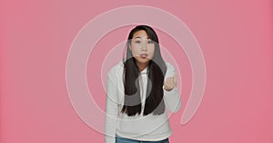 Give me cash. Pretty asian girl making money gesture, asking for payment, allowance, donation on pink studio background