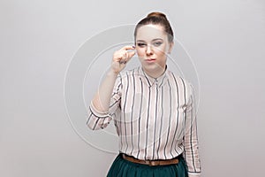 Give me a little bit more please. Portrait of hopeful beautiful young woman in striped shirt with makeup and collected ban