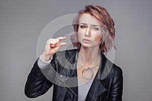 Give me a little bit. Portrait of hopeful beautiful girl with short hair and makeup in casual style black leather jacket standing