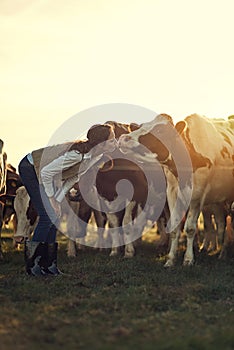 Give mommy a kiss. a female farmer pretending to kiss one of her cows in a field.