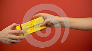 Give present from hand to hand on red background, holiday celebration concept