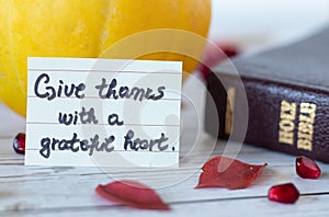 Give thanks with a grateful heart, a handwritten quote with Holy Bible Book and pumpkin.