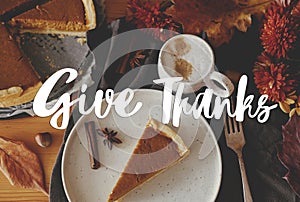 Give thanks text on pumpkin pie on rustic table with napkin, autumn leaves, spices, dinner rustic setting. Happy thanksgiving
