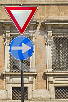 Give way and right arrow direction signs with ancient italian military accademy as background