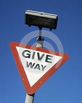 Give way road traffic sign against blue sky