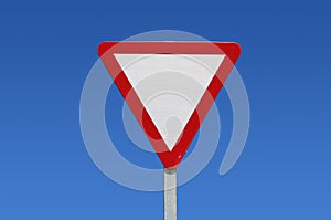 Give way, traffic or transit sign, white triangle and reds on a pole against a blue sky