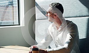 Give your goal your best shot. a mature businessman looking thoughtfully out of a window in a modern office.