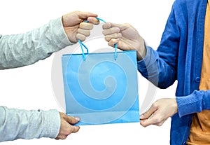 Giver hand holding blue paper bag with receiver