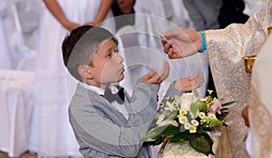 Gives holy communion to faithful boy