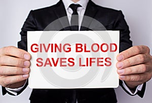 GIVING BLOOD ECONOMY OF LIFE inscription in red letters on a sheet of paper
