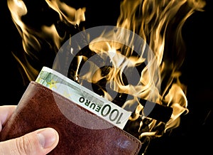 Giving bribe from brown leather wallet with one hundred Euro with burning fire isolated