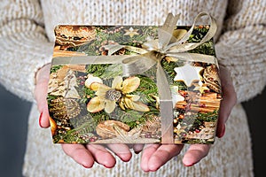 Giving a gift, handmade present wrapped in paper. Christmas time.