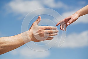 Giving a helping hand. Hands of man and woman on blue sky background. Lending a helping hand. Hands of man and woman