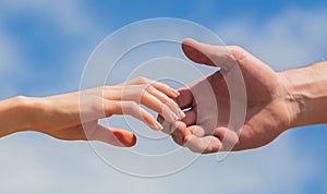 Giving a helping hand. Hands of man and woman on blue sky background. Lending a helping hand. Hands of man and woman