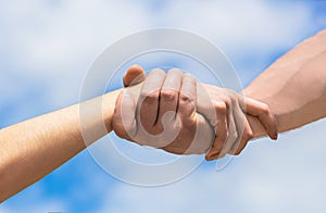 Giving a helping hand. Hands of man and woman on blue sky background. Lending a helping hand. Hands of man and woman