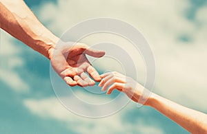 Giving a helping hand. Hands of man and woman reaching to each other, support. Hands of man and woman on blue sky