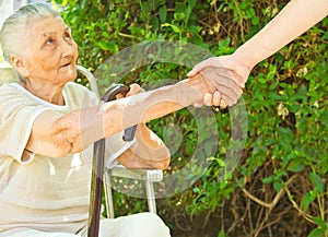 Giving a helping hand for a sitting old lady in the park photo