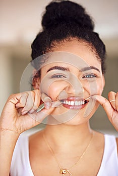 Giving her smile a thorough cleaning. Portrait of a young woman flossing her teeth.