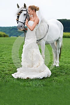 Giving her stallion the attention it deserves. A stunning young bride giving her beautiful stallion some affection.