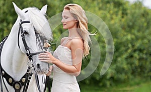 Giving her stallion the attention it deserves. A stunning young bride giving her beautiful stallion some affection.
