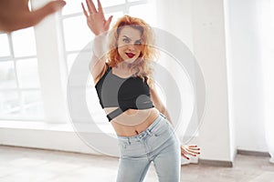 Giving high five. Attractive redhead woman posing in the spacey room near the window