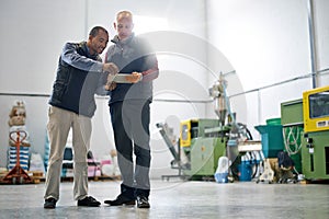 Giving his manager a status update. two factory managers using a tablet during a warehouse inspection.