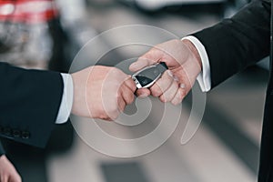 Giving a key from new car at dealership showroom