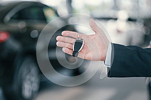 Giving a key from new car at dealership showroom