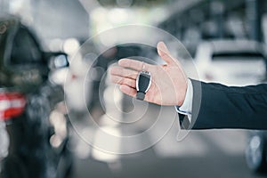 Giving a key from new car at dealership showroom